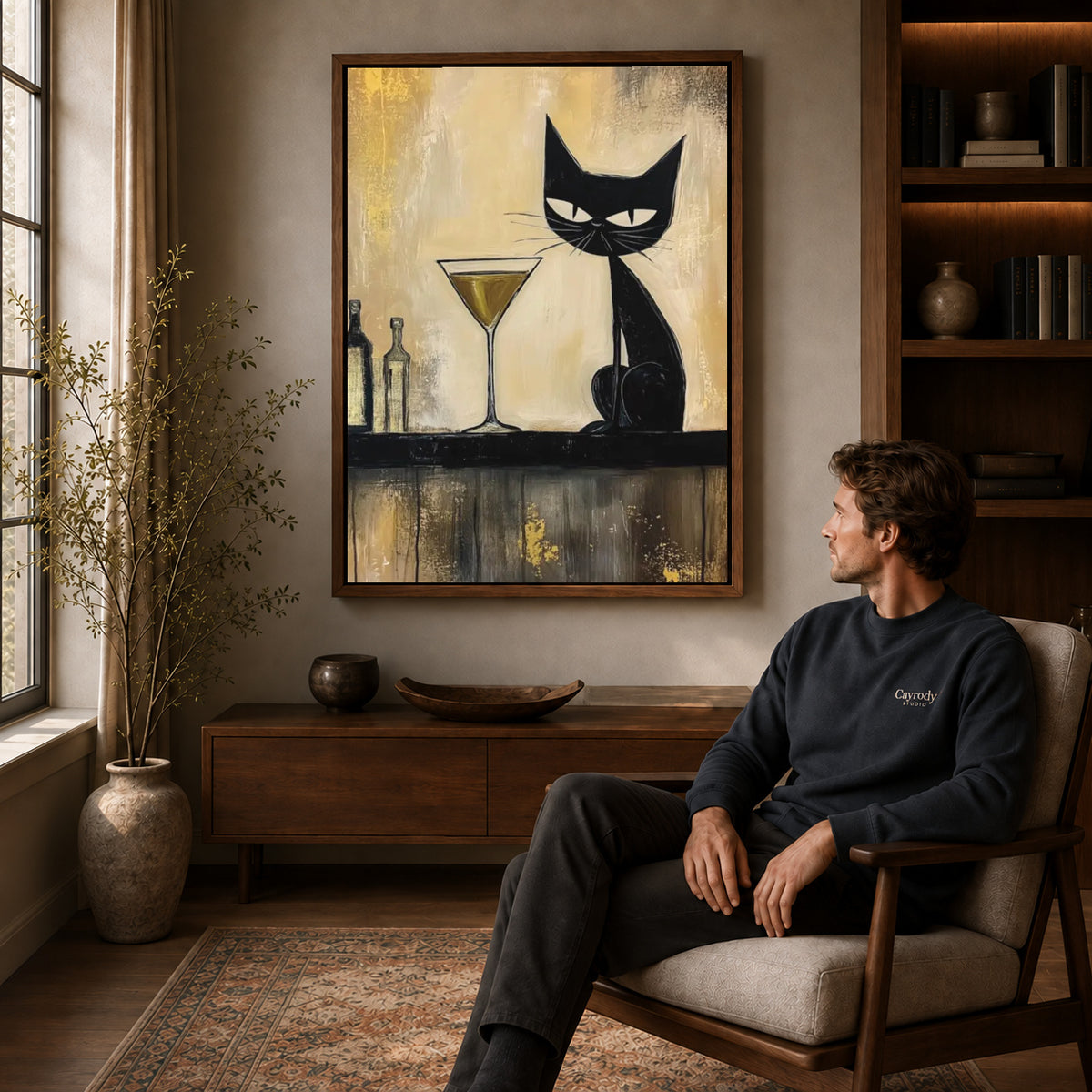 midnight martini cat canvas art in a walnut frame above a console beside a seated man.