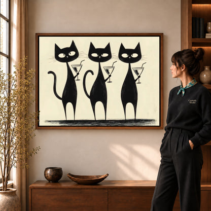 cocktail cat trio canvas art in a walnut frame beside a standing woman and wooden console.