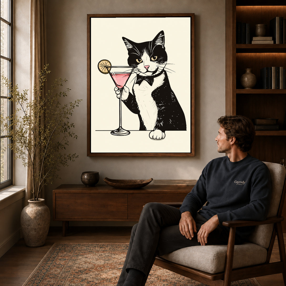tuxedo cocktail cat canvas art in a walnut frame above a console beside a seated man.