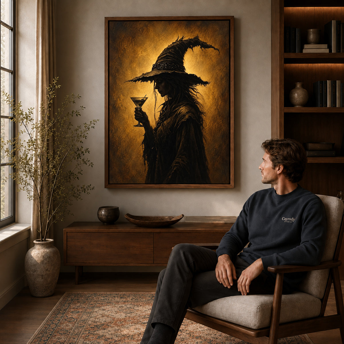 golden twilight witch canvas art in a walnut frame above a console beside a seated man.