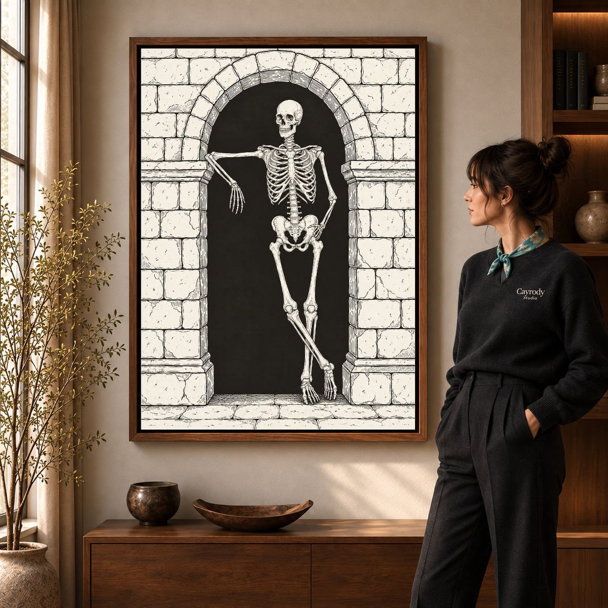 leaning skeleton guest canvas art in a walnut frame beside a standing woman and wooden console.