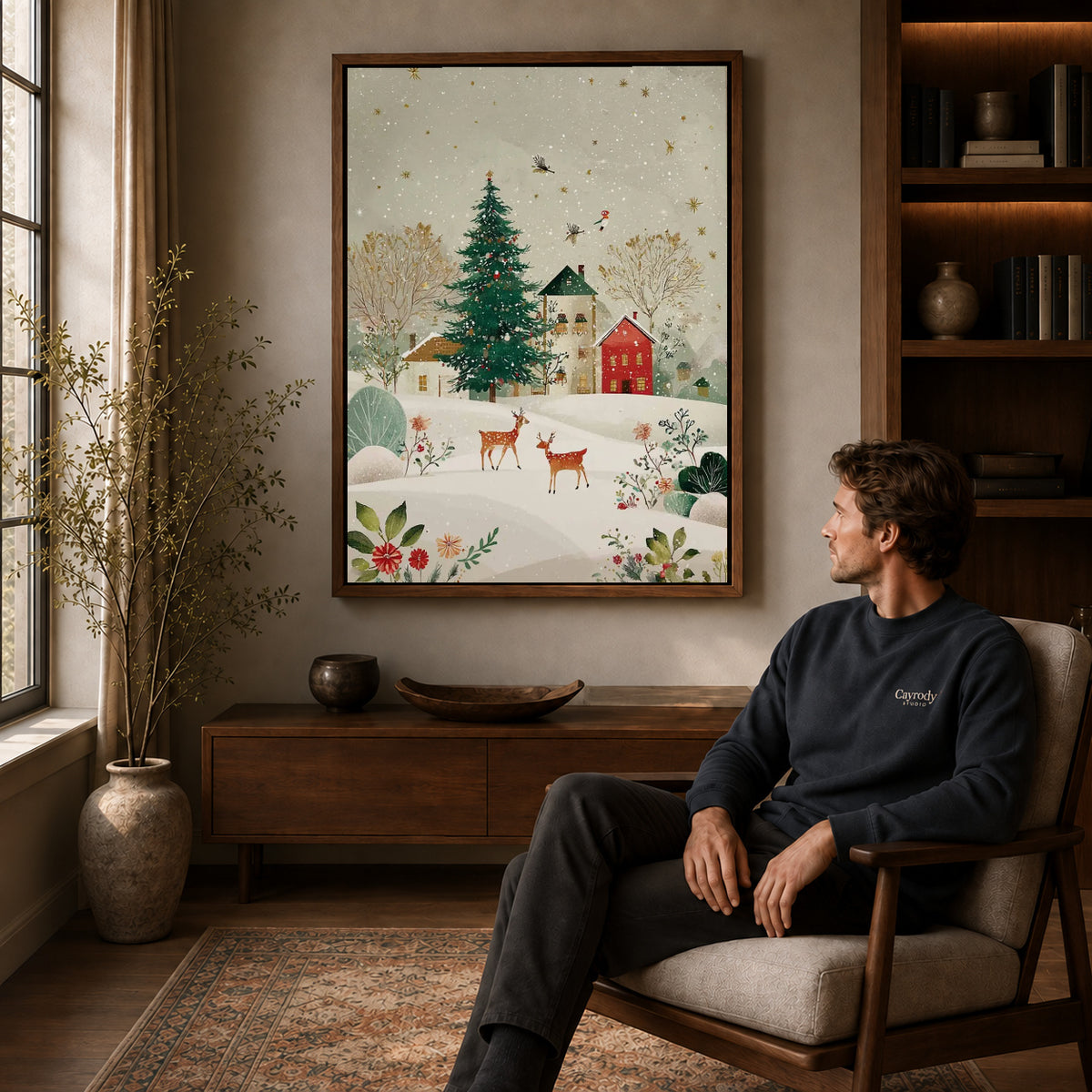 snowy village deer canvas art in a walnut frame above a console beside a seated man.