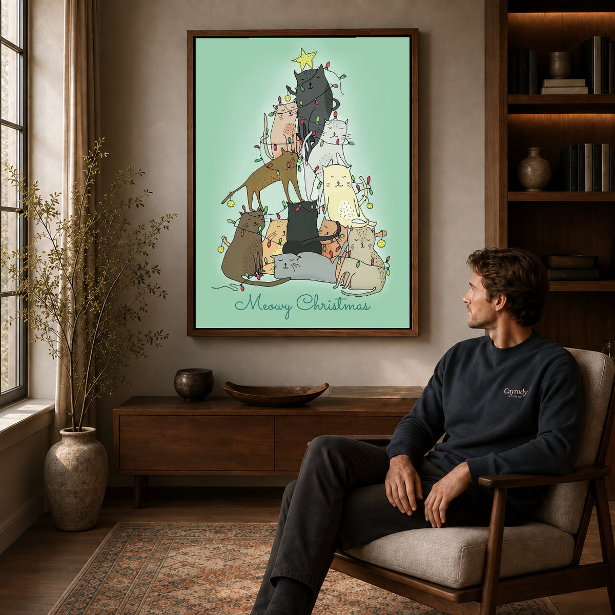 meowy christmas cats canvas art in a walnut frame above a console beside a seated man.
