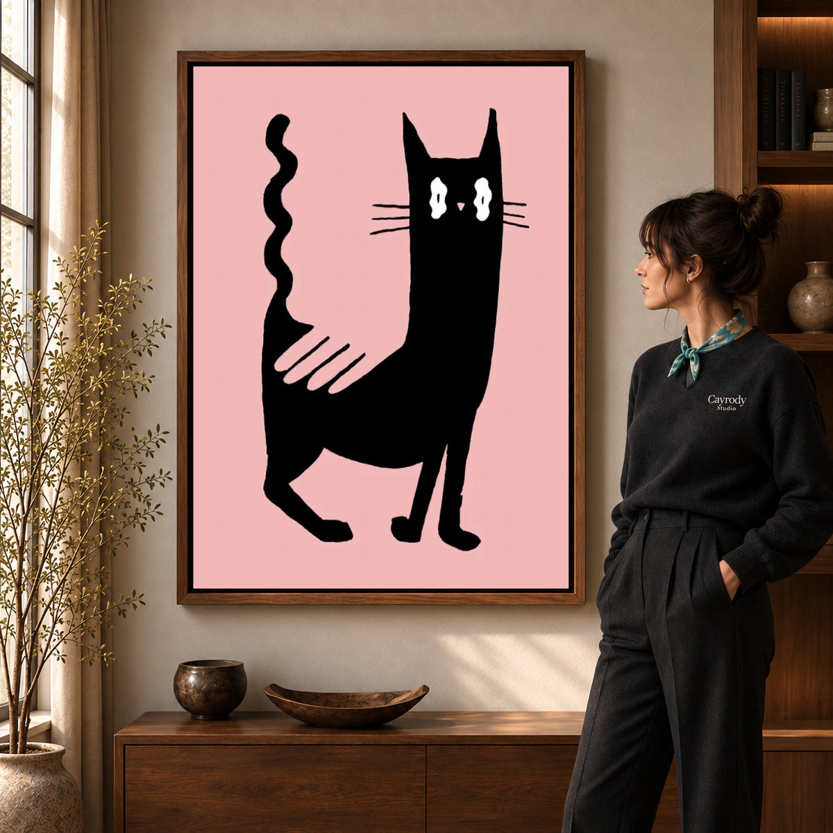 wavy tail cat canvas art in a walnut frame beside a standing woman and wooden console.
