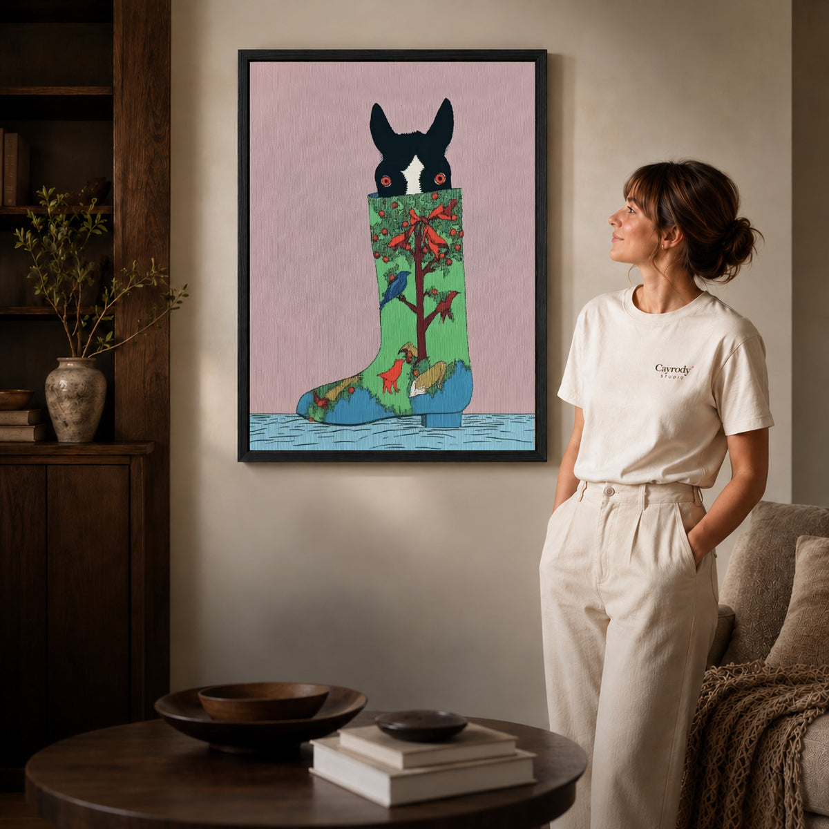 christmas stocking pup canvas art in a black frame beside a woman and round wooden table.