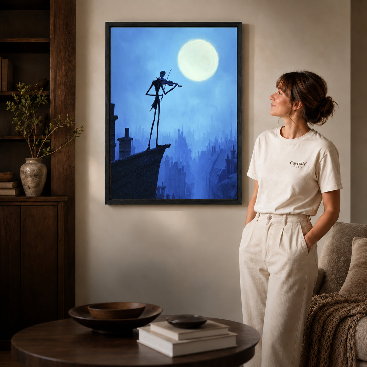 moonlit rooftop violin canvas art in a black frame beside a woman and round wooden table.