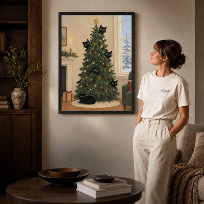 christmas tree cats canvas art in a black frame beside a woman and round wooden table.