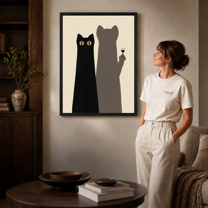 cat shadow toast canvas art in a black frame beside a woman and round wooden table.