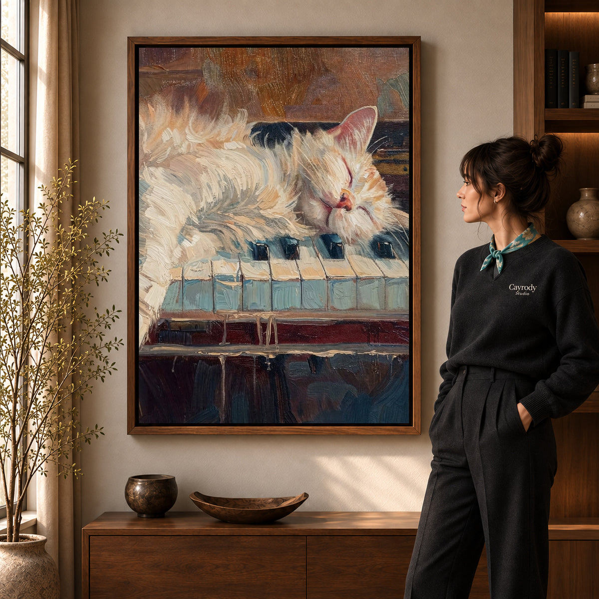 sleepy piano cat canvas art in a walnut frame beside a standing woman and wooden console.