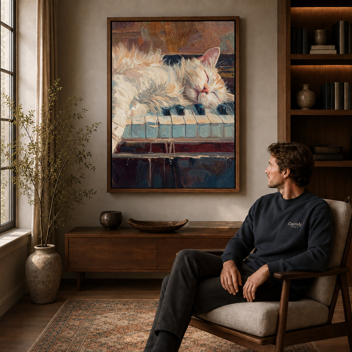 sleepy piano cat canvas art in a walnut frame above a console beside a seated man.