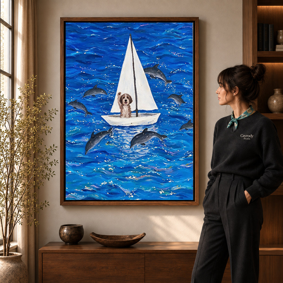 seafaring dog adventure canvas art in a walnut frame beside a standing woman and wooden console.