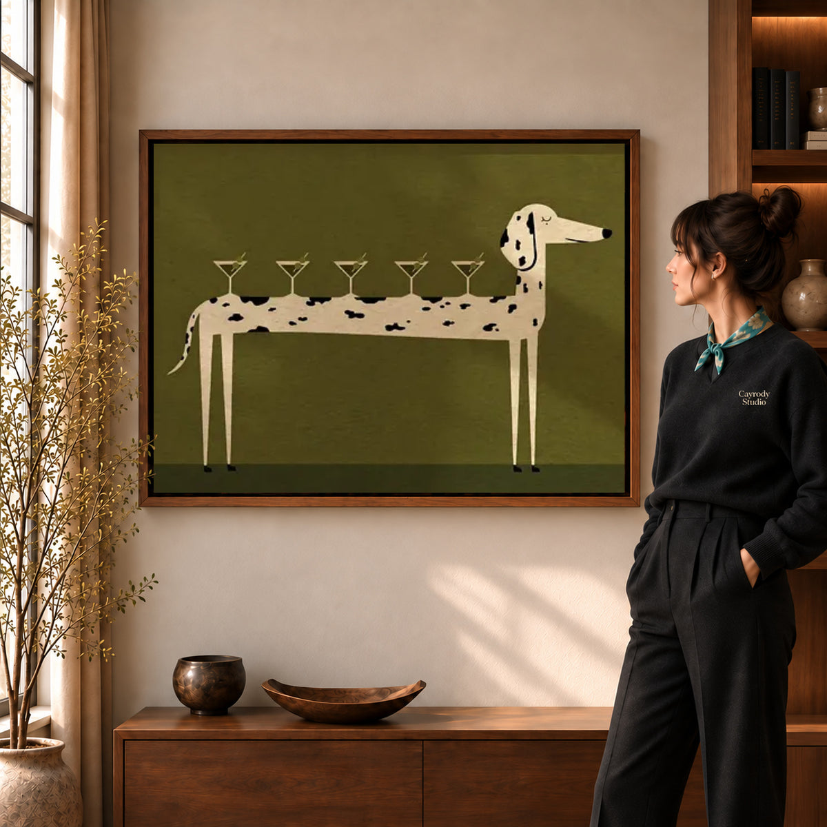 cocktail canine balance canvas art in a walnut frame beside a standing woman and wooden console.