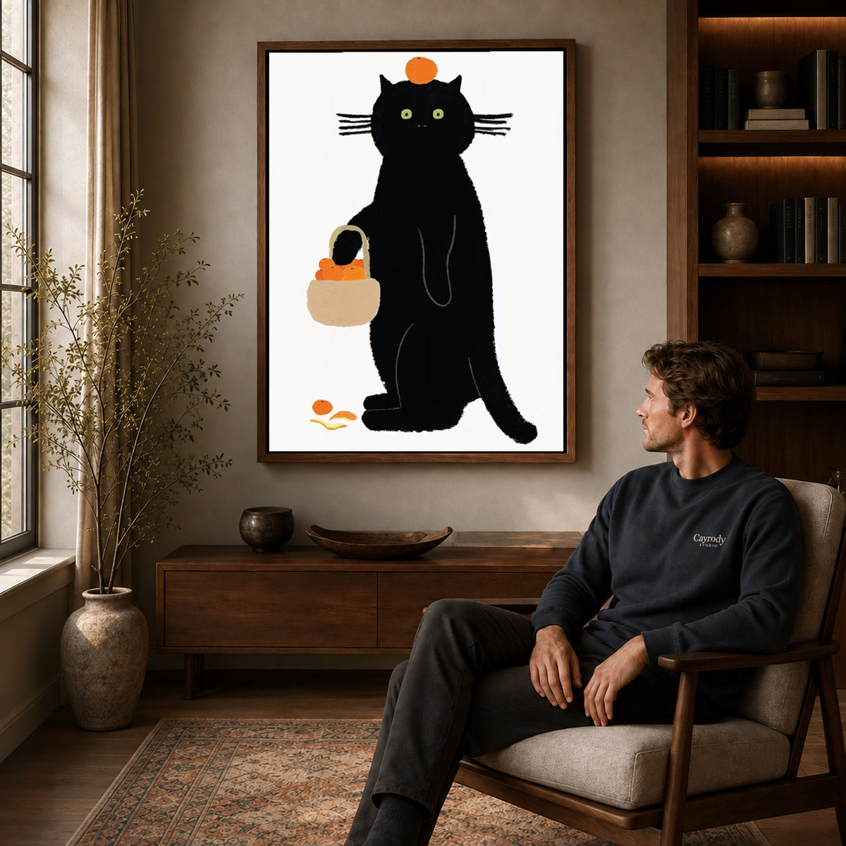 orange basket cat canvas art in a walnut frame above a console beside a seated man.
