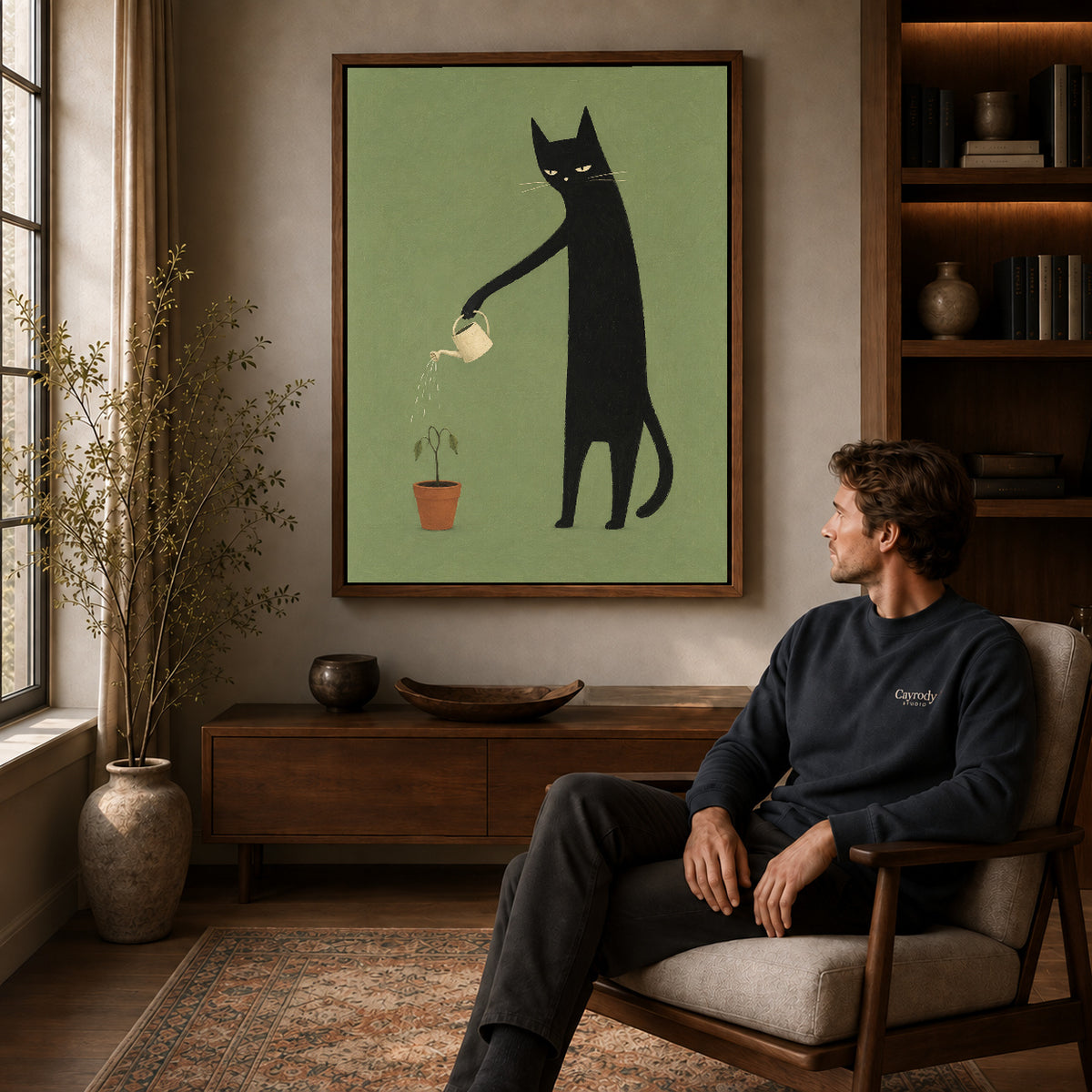 reluctant garden cat canvas art in a walnut frame above a console beside a seated man.