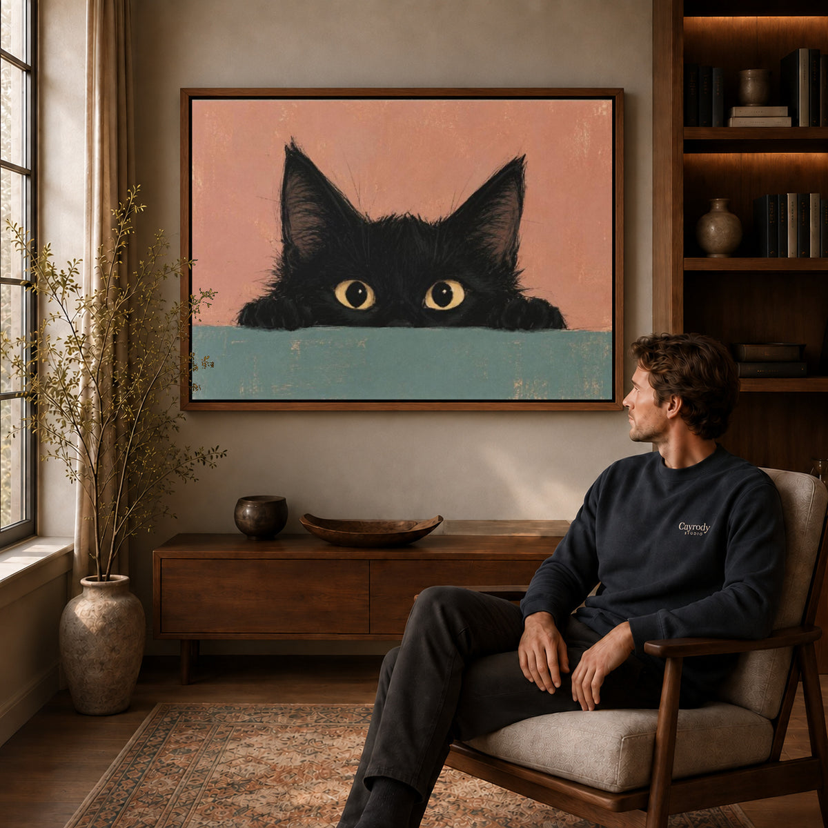 curious peeking kitten canvas art in a walnut frame above a console beside a seated man.