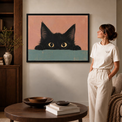 curious peeking kitten canvas art in a black frame beside a woman and round wooden table.