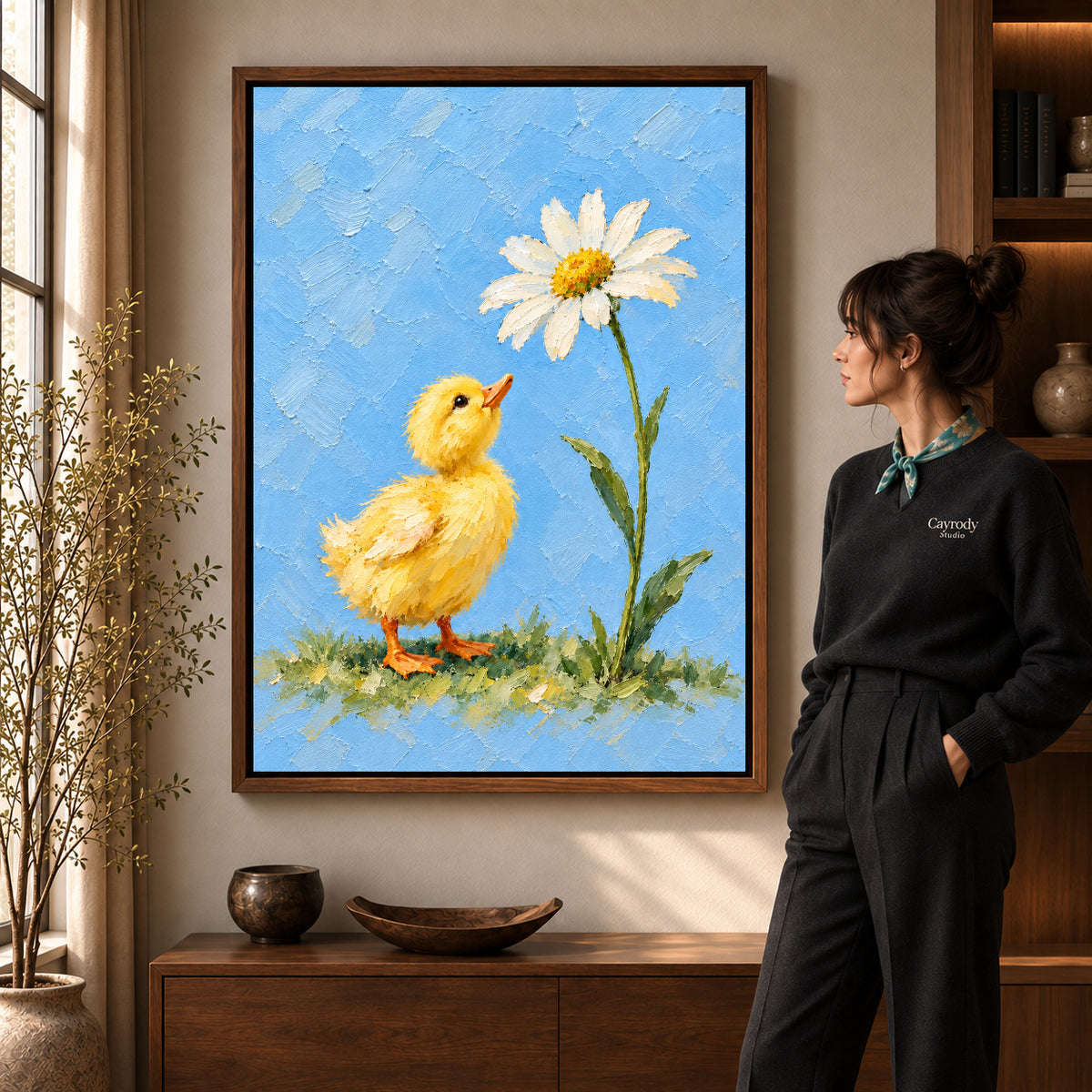 duckling daisy wonder canvas art in a walnut frame beside a standing woman and wooden console.
