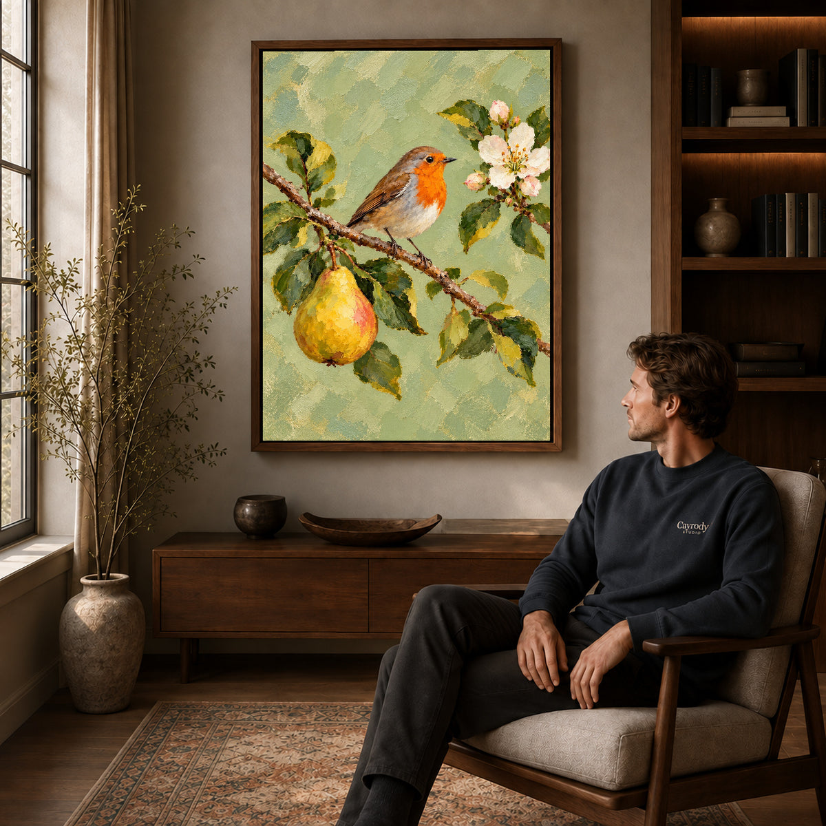 robin pear blossoms canvas art in a walnut frame above a console beside a seated man.