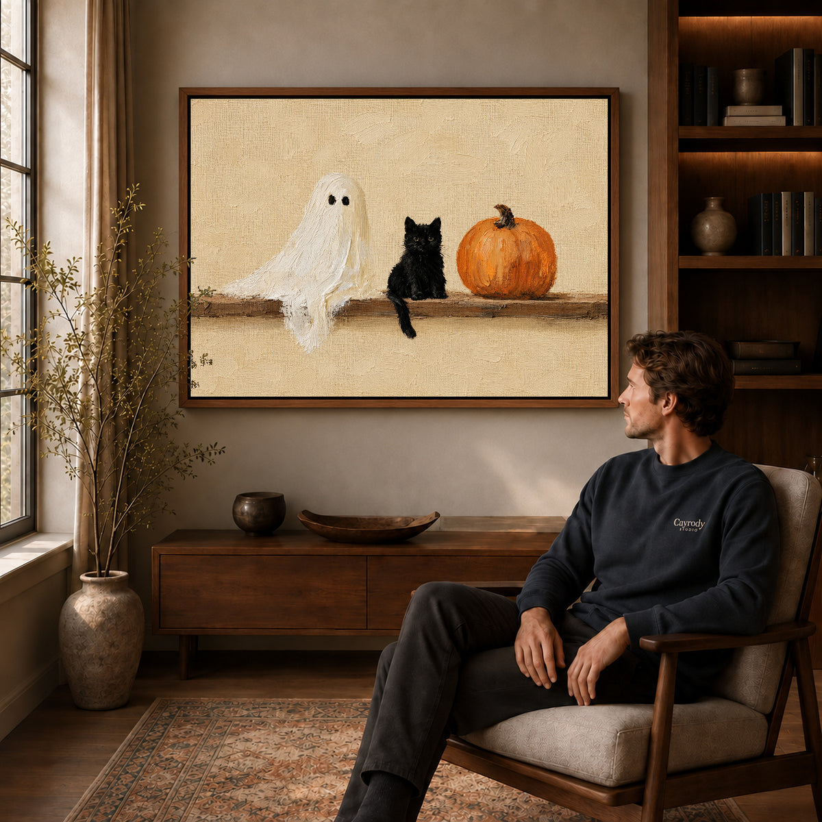 ghost kitten gathering canvas art in a walnut frame above a console beside a seated man.