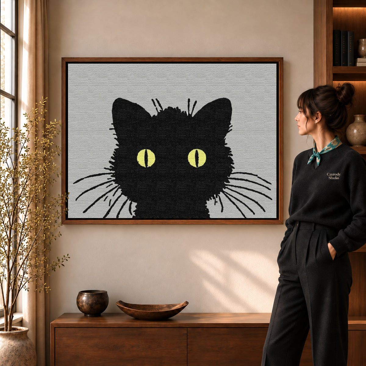 golden eye cat canvas art in a walnut frame beside a standing woman and wooden console.
