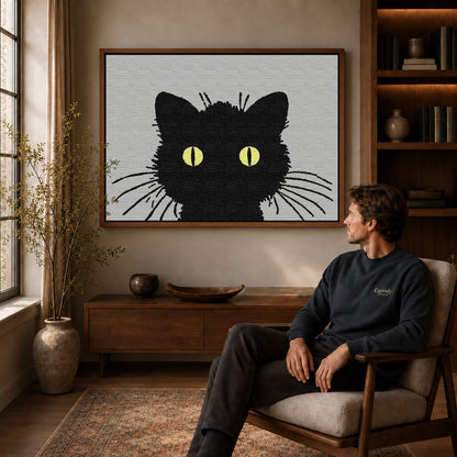 golden eye cat canvas art in a walnut frame above a console beside a seated man.