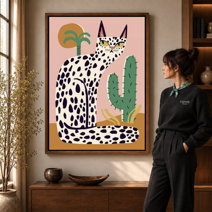 spotted desert cat canvas art in a walnut frame beside a standing woman and wooden console.
