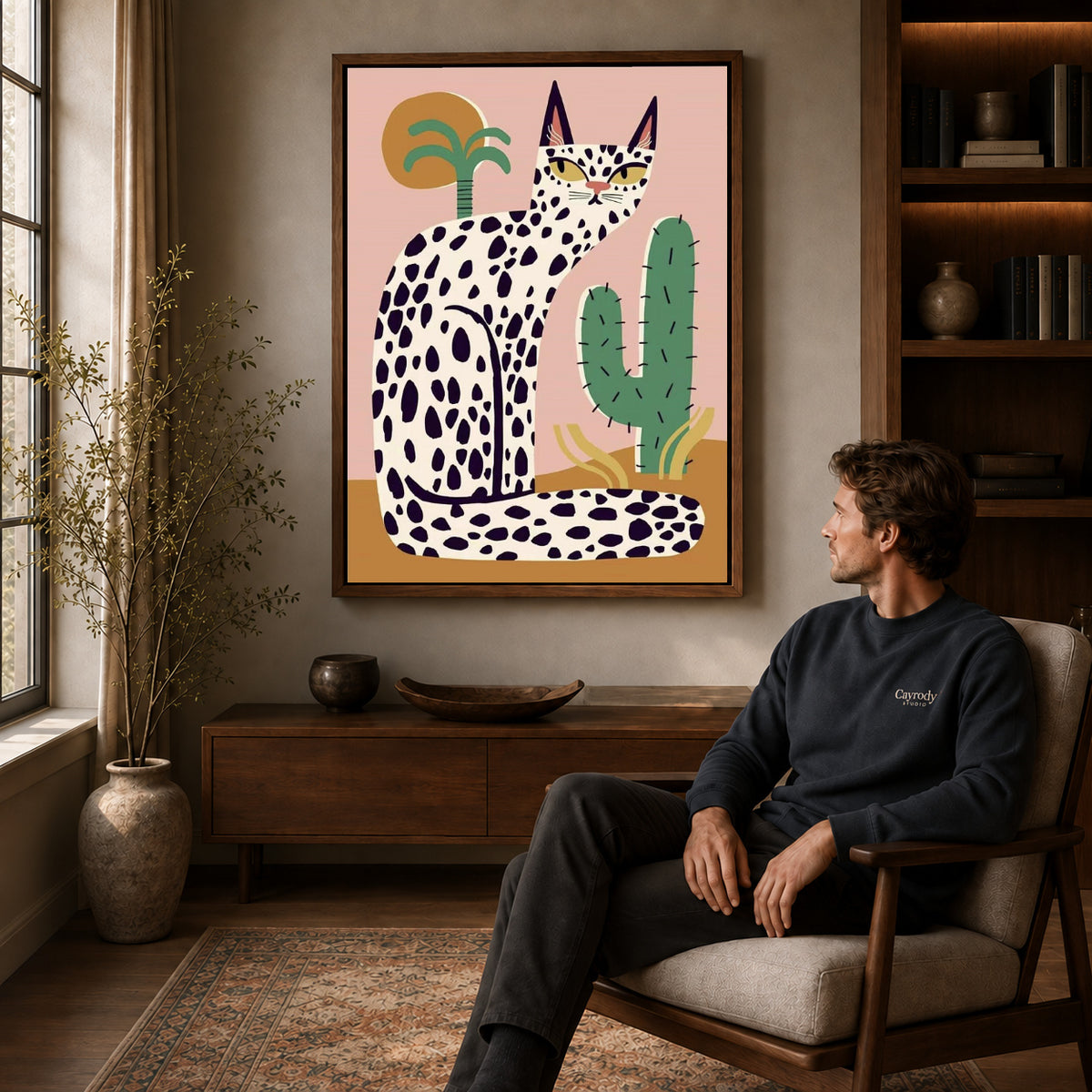 spotted desert cat canvas art in a walnut frame above a console beside a seated man.
