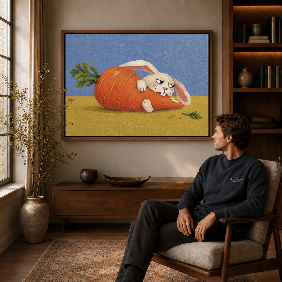 carrot hideaway rabbit canvas art in a walnut frame above a console beside a seated man.