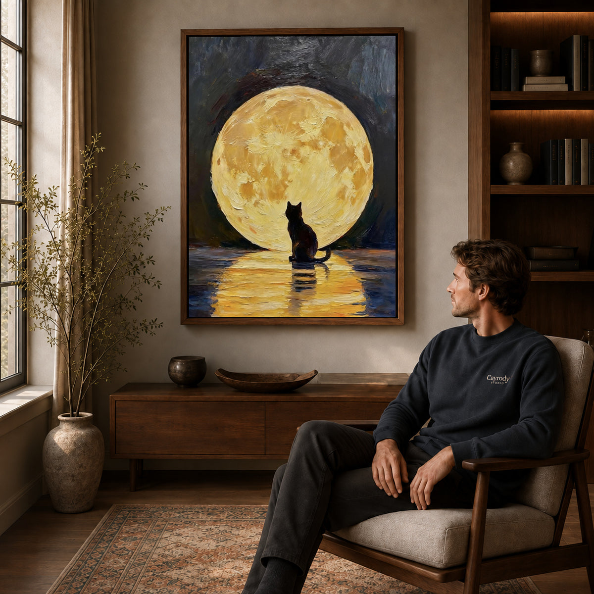 golden moon cat canvas art in a walnut frame above a console beside a seated man.