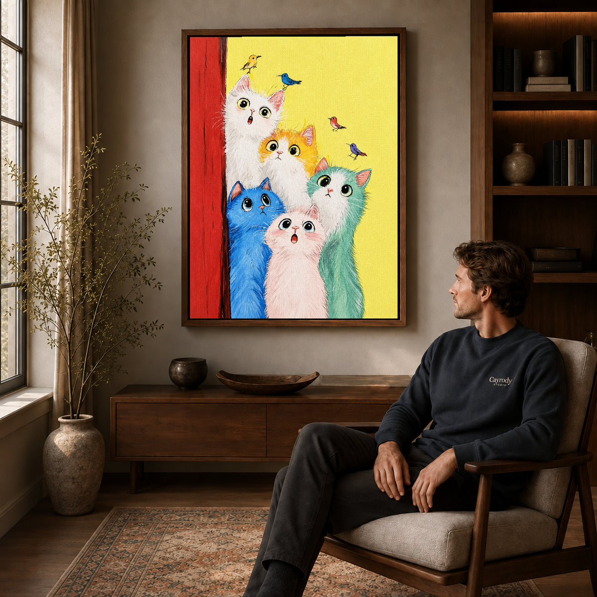 colorful cat chorus canvas art in a walnut frame above a console beside a seated man.