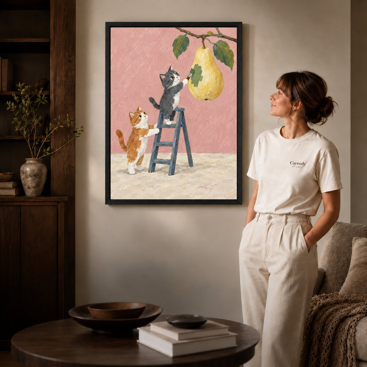 little pear painters canvas art in a black frame beside a woman and round wooden table.