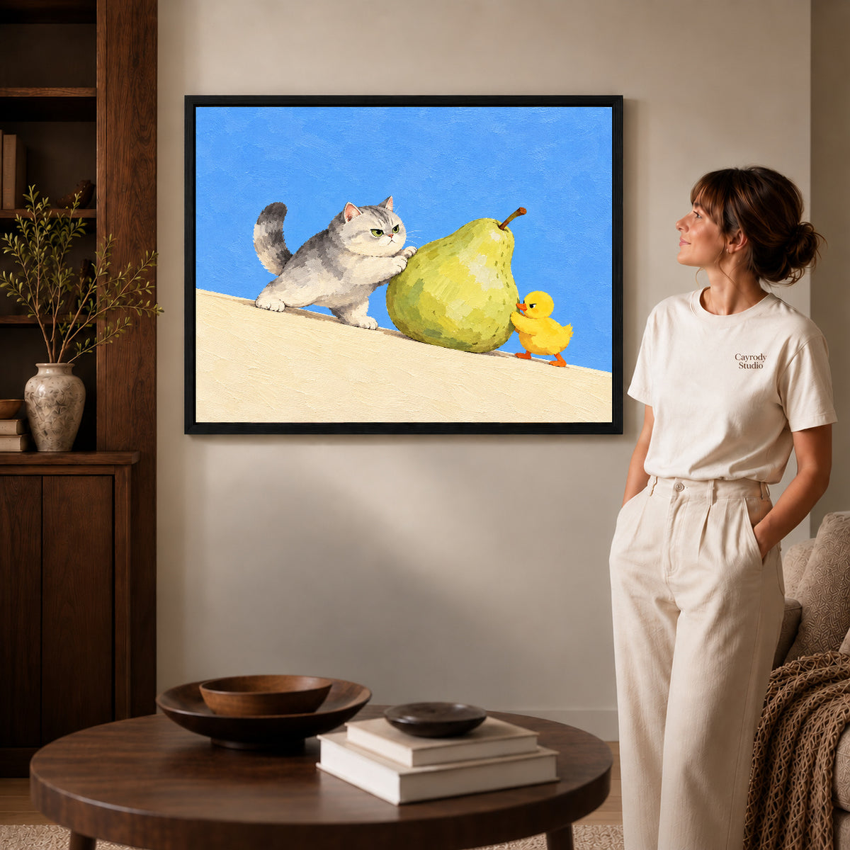pear push partners canvas art in a black frame beside a woman and round wooden table.