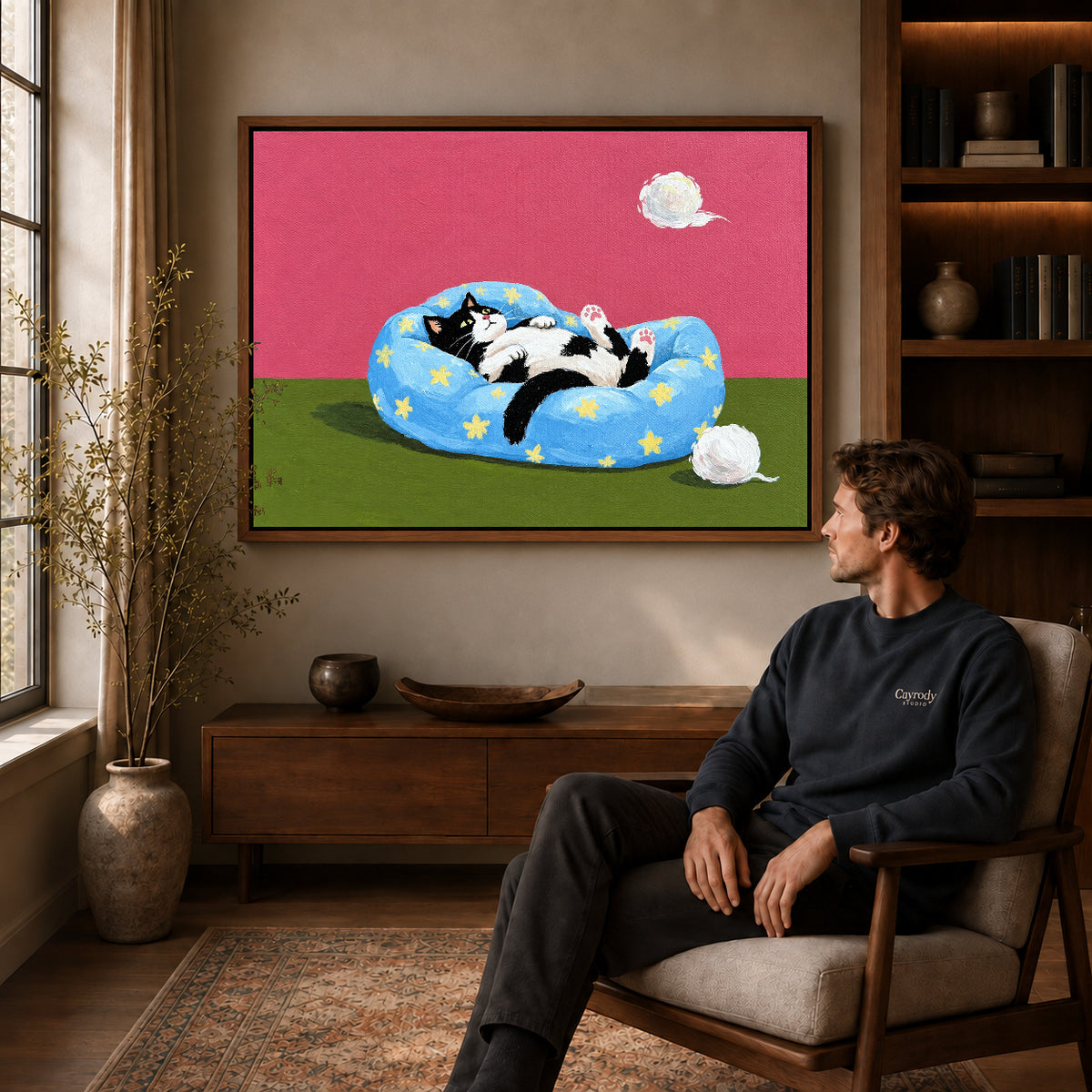 star bed cat canvas art in a walnut frame above a console beside a seated man.