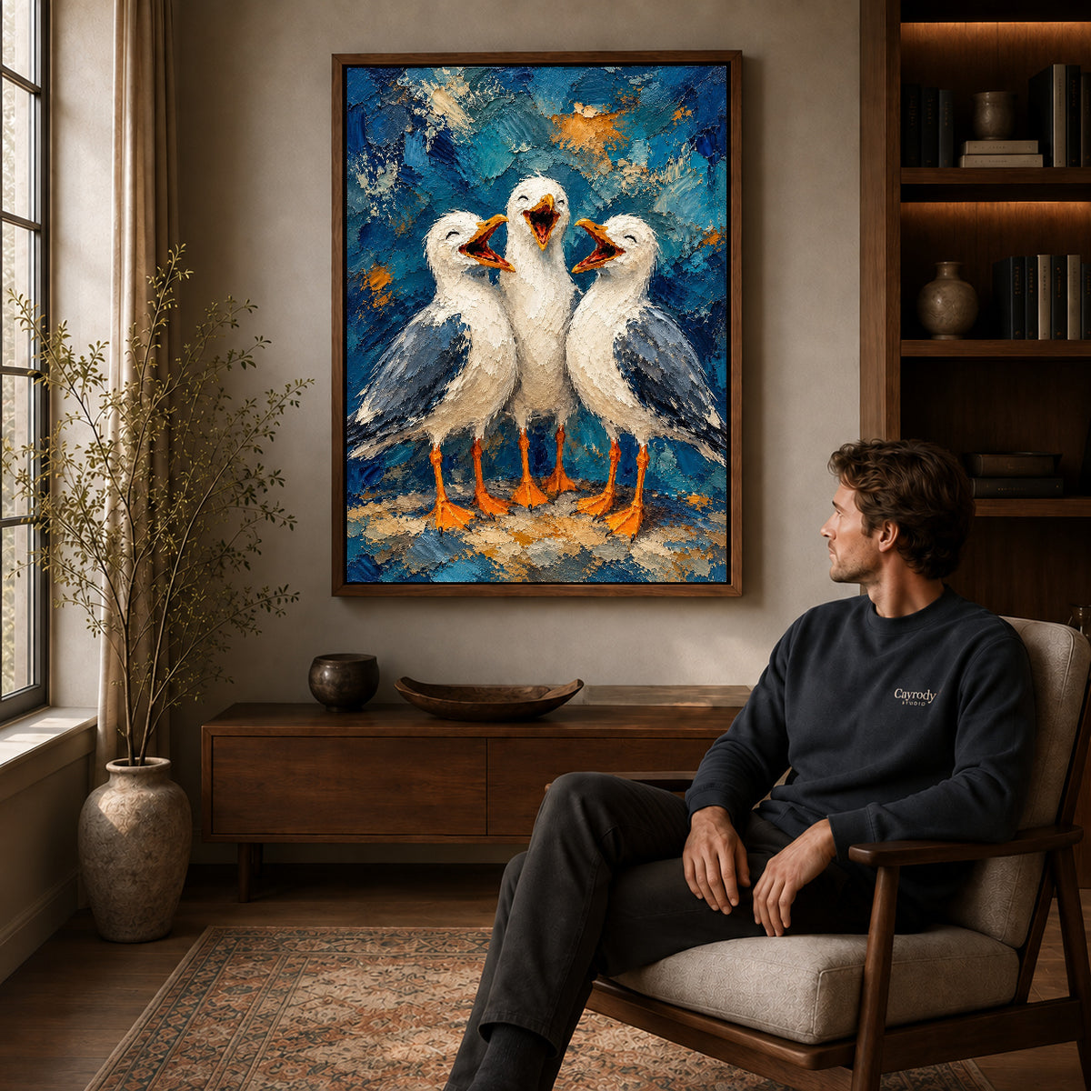 laughing seagull trio canvas art in a walnut frame above a console beside a seated man.
