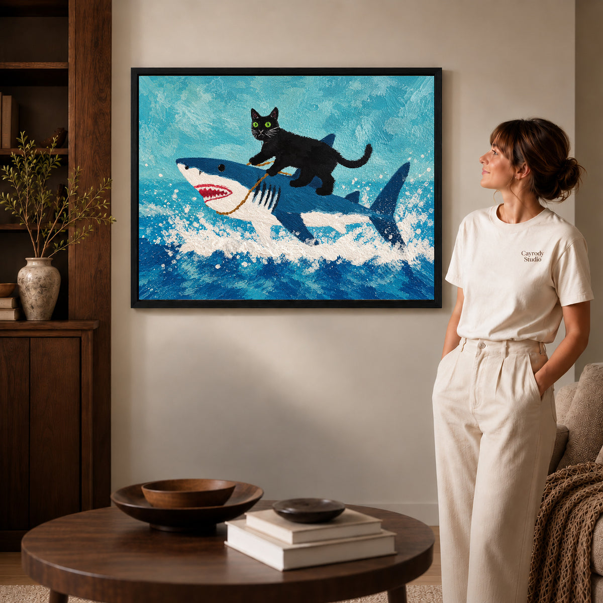cat shark adventure canvas art in a black frame beside a woman and round wooden table.