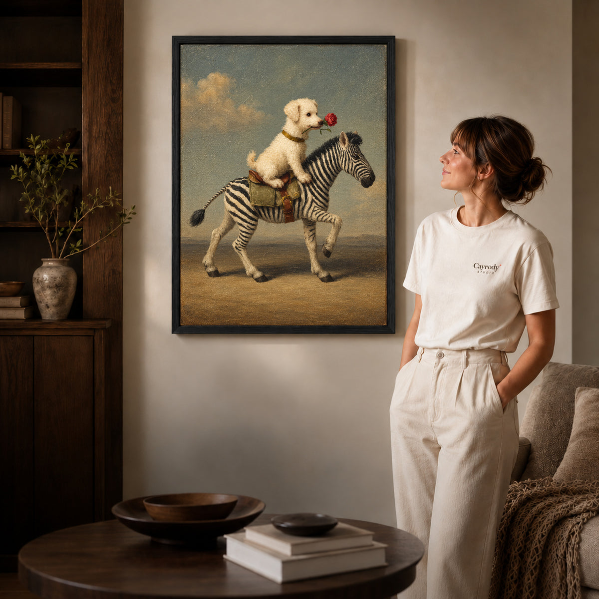 puppy zebra journey canvas art in a black frame beside a woman and round wooden table.