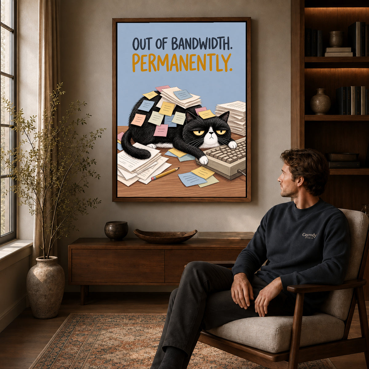 out of bandwidth canvas art in a walnut frame above a console beside a seated man.
