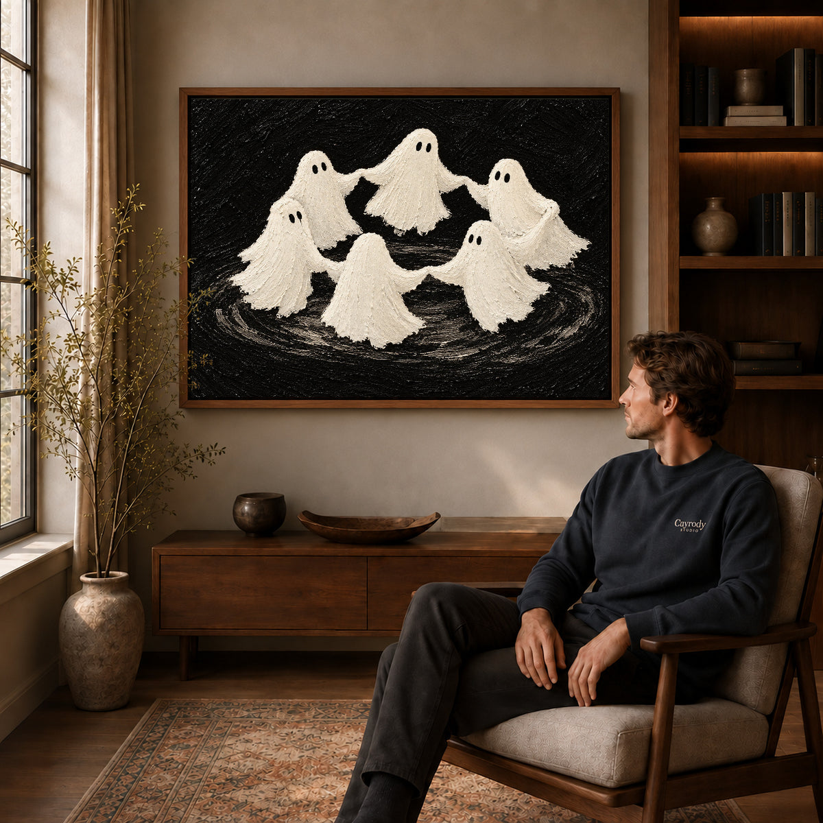 dancing ghost circle canvas art in a walnut frame above a console beside a seated man.