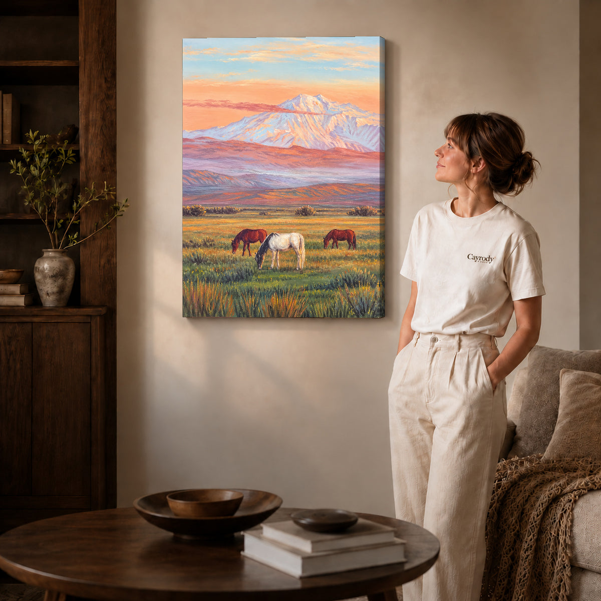pastel mountain horses canvas art on gallery-wrapped canvas with natural edge shading beside a standing woman.