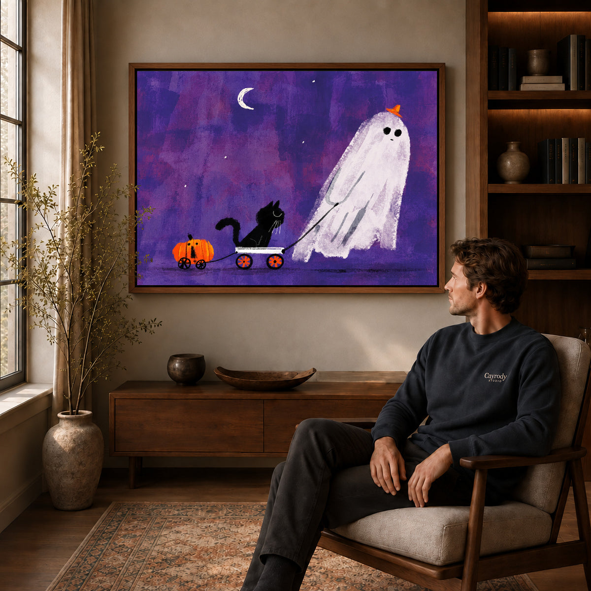 ghost wagon outing canvas art in a walnut frame above a console beside a seated man.
