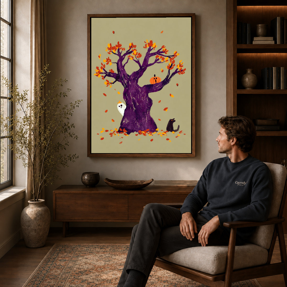 autumn ghost tree canvas art in a walnut frame above a console beside a seated man.