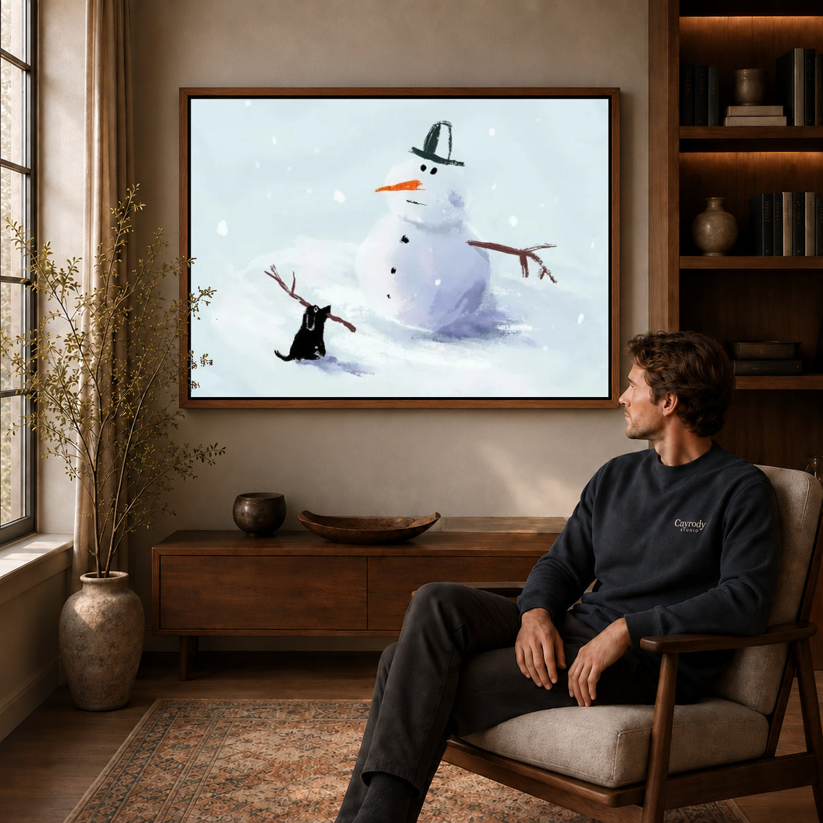 snowman stick mischief canvas art in a walnut frame above a console beside a seated man.