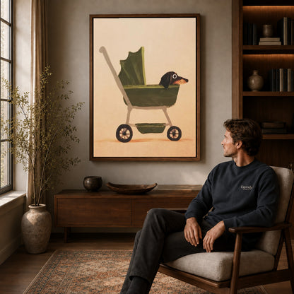 dachshund pram ride canvas art in a walnut frame above a console beside a seated man.