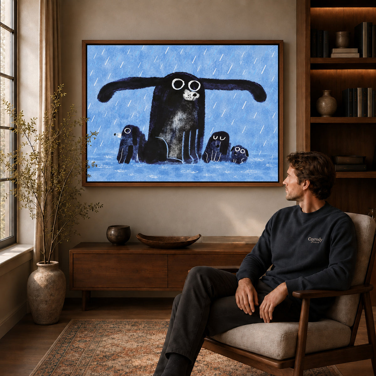 sheltering dog family canvas art in a walnut frame above a console beside a seated man.
