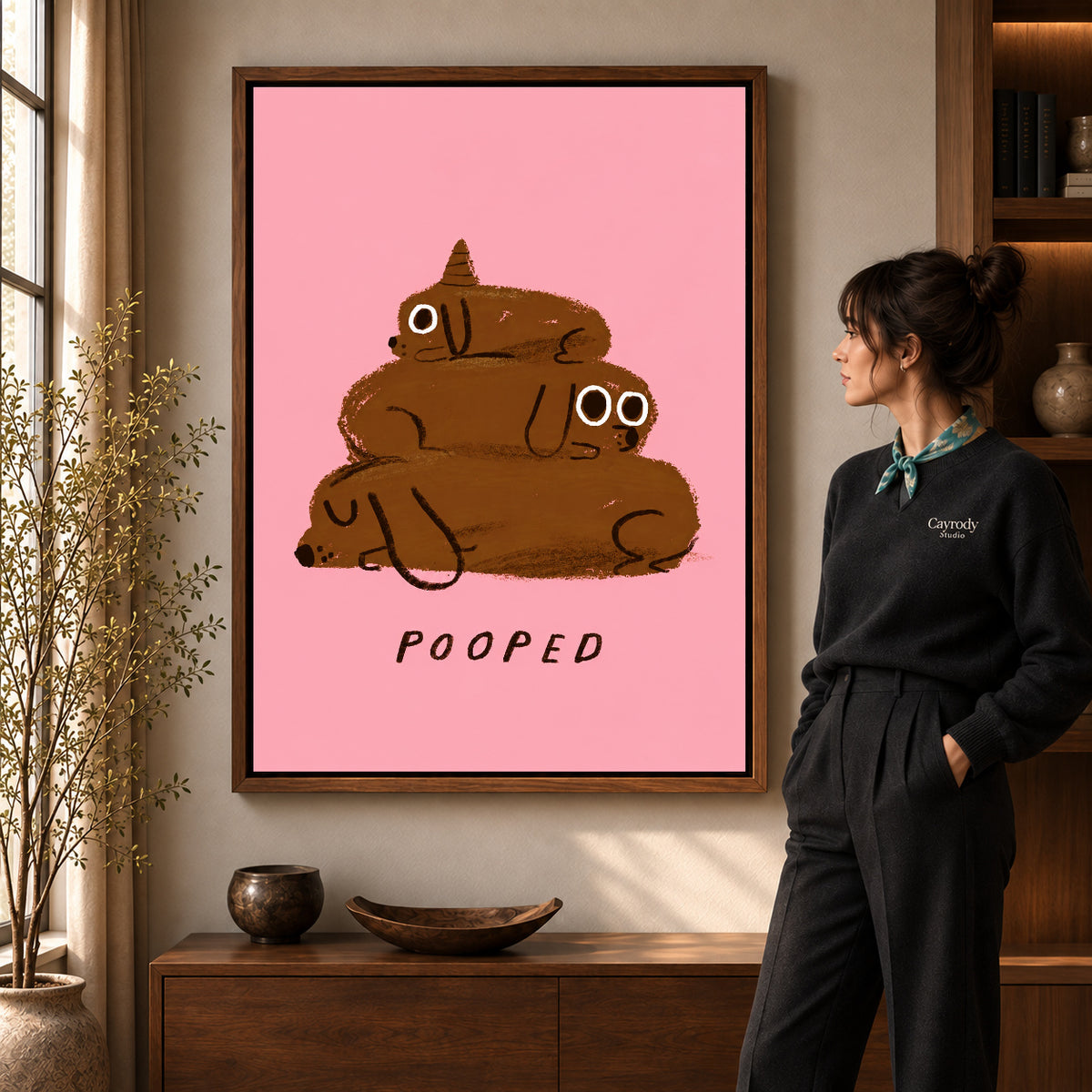 pooped puppy stack canvas art in a walnut frame beside a standing woman and wooden console.