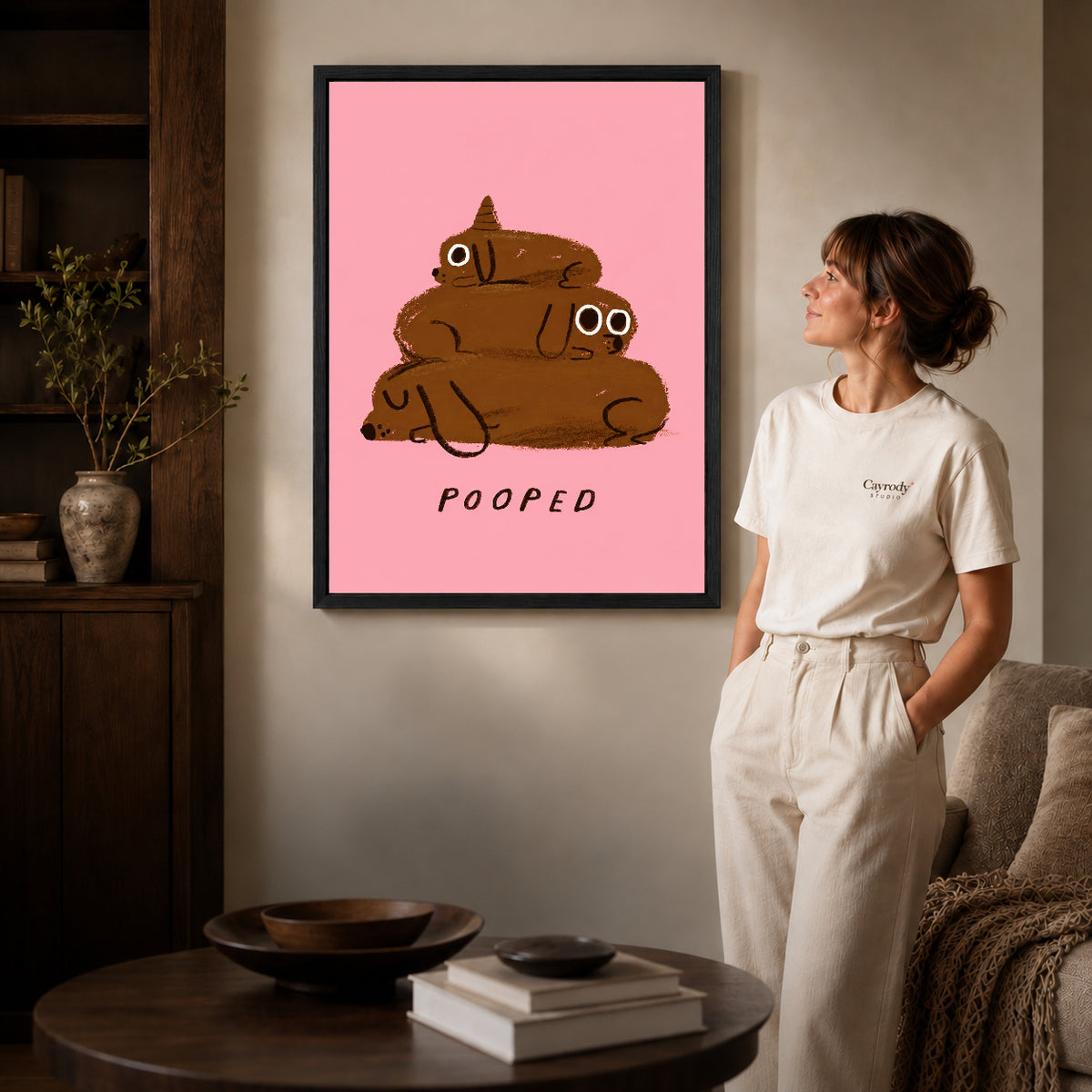 pooped puppy stack canvas art in a black frame beside a woman and round wooden table.