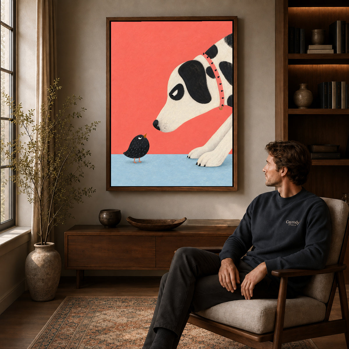 dog meets tiny bird canvas art in a walnut frame above a console beside a seated man.