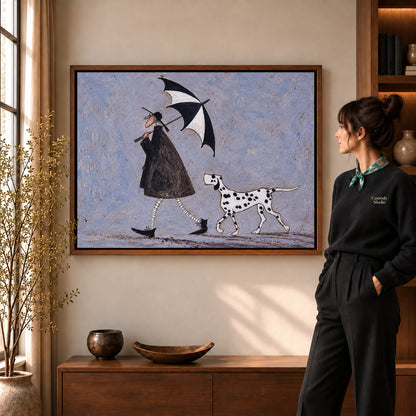 umbrella walk companions canvas art in a walnut frame beside a standing woman and wooden console.