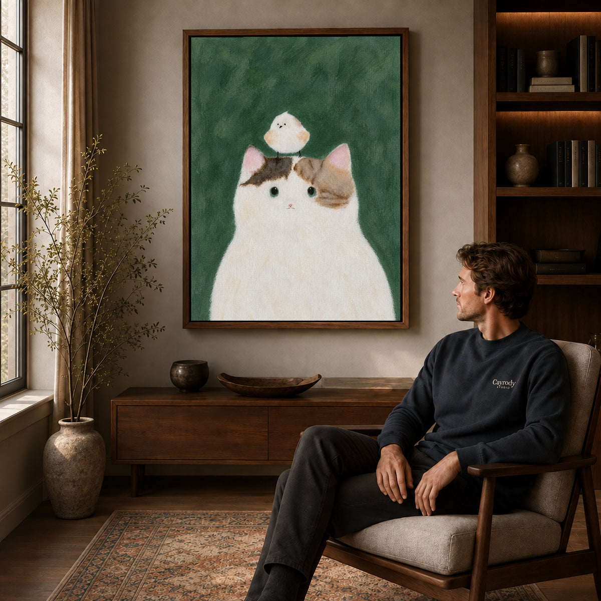 cat bird gentle friendship canvas art in a walnut frame above a console beside a seated man.