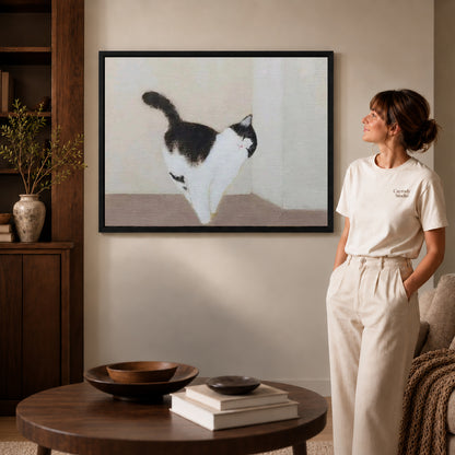 quiet cat stroll canvas art in a black frame beside a woman and round wooden table.